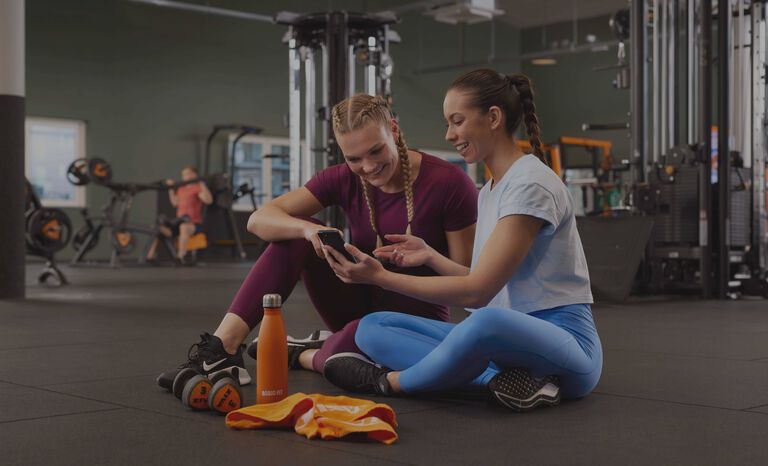 Two ladies checking out the Basic-Fit app